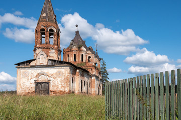 a dilapidated Church and a fence on a summer day