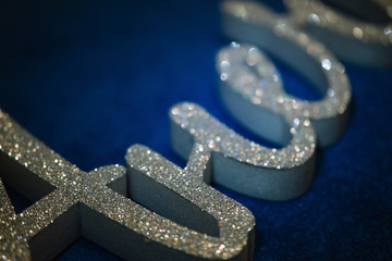 Letter and word from gray extruded polystyrene foam painted in silver glitter. decor lies on a dark blue background. blank for decoration, logo making.