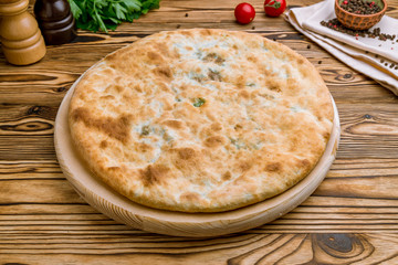 Ossetian pie with spinach on old wooden table
