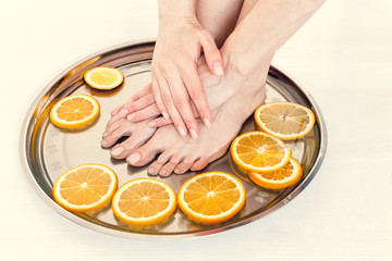 Obraz na płótnie Canvas pedicure and manicure in the spa salon with sliced oranges