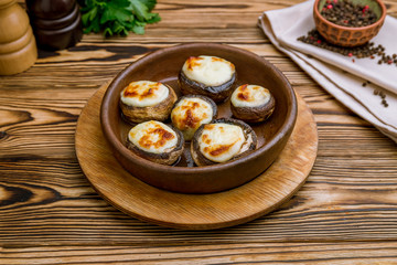 mushrooms baked with Suluguni cheese on wooden table