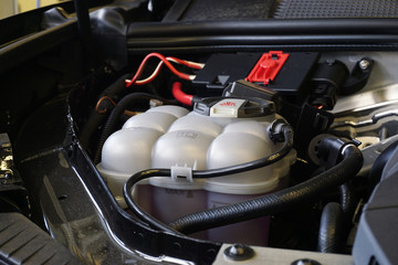 Close-up white expansion tank with pink antifreeze. Car coolant level in radiator system in car,...