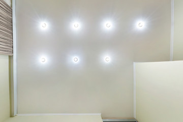 suspended ceiling with led lightspot lamps and drywall construction in empty room in apartment or house. Stretch ceiling white and complex shape. looking up