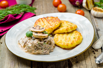 beef Stroganoff with potato pancakes on wooden table