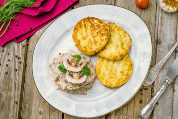 beef Stroganoff with potato pancakes on wooden table