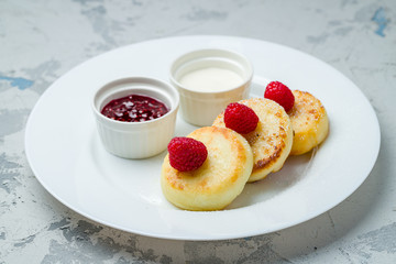 cheesecakes from cottage cheese with raspberries on white plate
