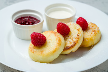 cheesecakes from cottage cheese with raspberries on white plate