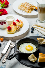 Breakfast on the table: cheesecakes, fried eggs, pancakes and coffee