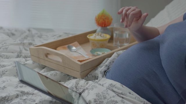 Pregnant Woman Uses Tablet To Video Chat, Waves Hello, From Bed Over Breakfast