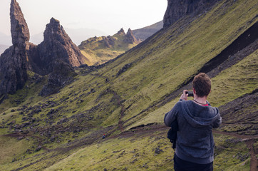 Man taking picture of rock sculpture old man of storr