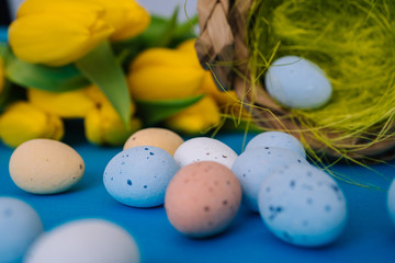 Happy Easter. Easter holiday decorations on trendy colored classic blue background. Creative spring composition with Easter elements - flowers and eggs in basket. Celebrating Easter concept at spring