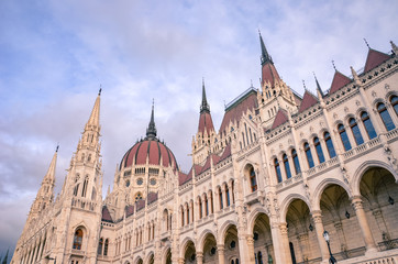 Fototapeta na wymiar Building of the Hungarian Parliament Orszaghaz in Budapest, Hungary. The seat of the National Assembly. House built in neo-gothic style. Sunset light, pink and purple sky and clouds above