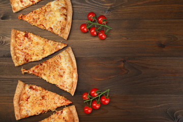 pieces of pizza and tomatoes cherry on brown wood table