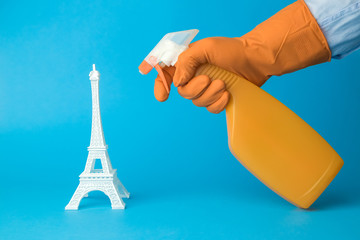 Hand in gloves using disinfectant to disinfect Eiffel Tower. France and covid-19 virus pandemic abstract.