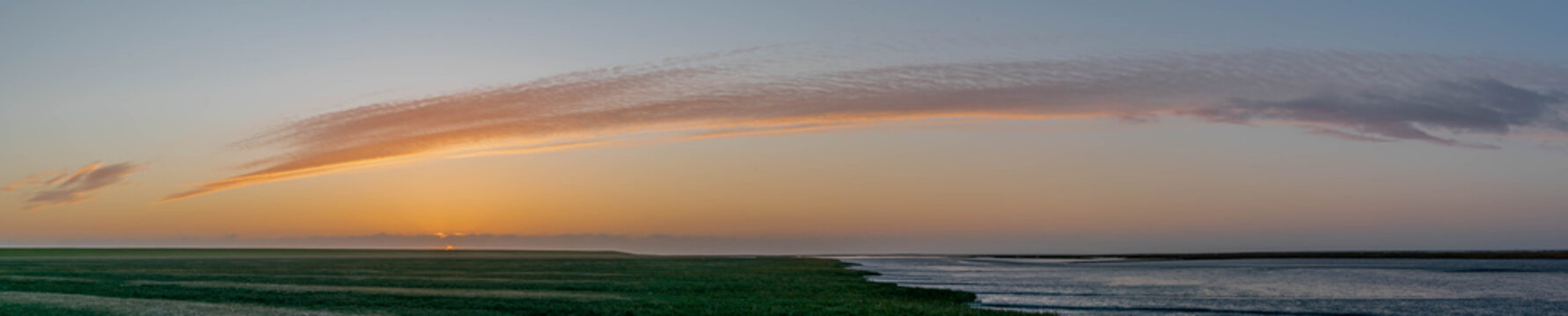An impressive panorama view of the dike foreland near the imposing Lighthouse Westerheversand, Sunset over the the Wadden Sea, mudflat, tideland on the Northsea T&uuml;mlauer-Koog