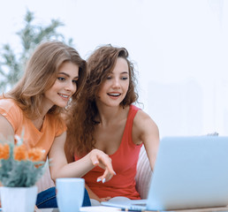 two young women discuss the video with laptop sitting at a coffee table