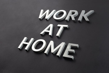 the words work at home laid with silver metal letters on matte black background in diagonal...