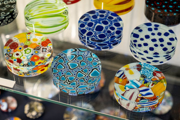 Decorative Murano glass pendants exposed in a glass case with reflection. Stained glass typical...