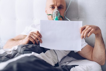 Coronavirus sick patient breathing through oxygen mask and holding empty card