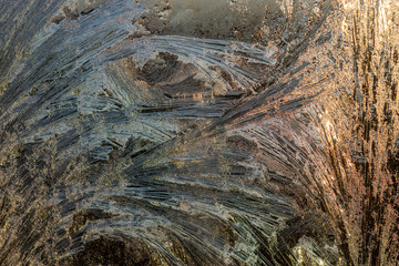 Frozen window in the morning sun, shimmering in warm colors. Frosty dawn in frozen glass.