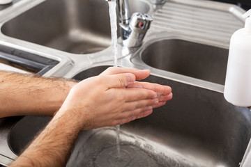 Man washing hands with antibacterial soap and water in metal sink for corona virus prevention. Hand hygiene, health care, medical concept. Hand skin disinfection protect from Coronavirus covid 19