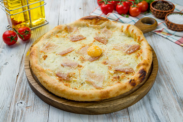 Carbonara pizza with bacon on white wooden table