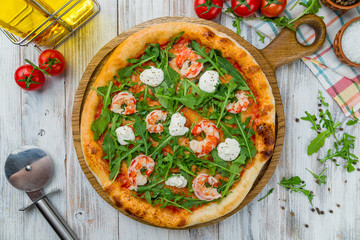 Pizza with arugula and shrimp on white wooden table