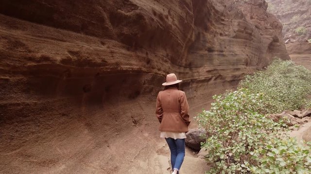 "Woman walking inside in ravine with big stones