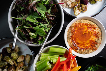 Healthy Green food such as peppers, celery, lettuce and hummus served on a dark table. Health and clean eating.