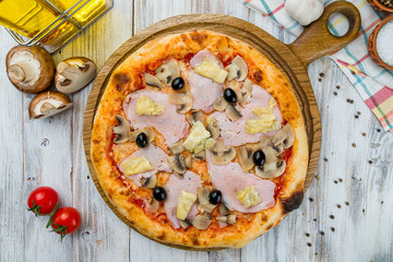 Capricciosa pizza with artichokes on white wooden table