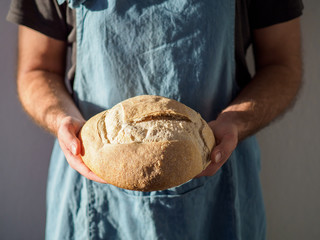 Man holding beautiful loaf of sourdough bread.