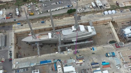 Aerial view of sea dry dock in La Ciotat city, France, the cargo crane, boats on repair, a luxury sail yacht and motor yacht, mountain is on background, shipyard