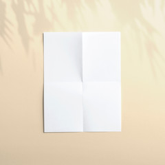Blank paper folded poster flyer letterhead on orange background with soft shadows and floral light overlay as template for design presentation, promotion, portfolios etc.