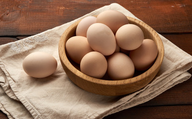 raw brown homemade chicken eggs in a wooden plate on the table