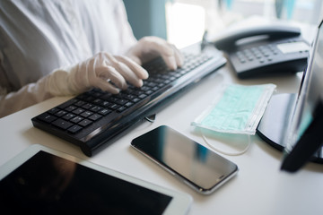 Close up on hands in medical gloves typing on keyboard. Protective care. Emergency problem. Healthcare employee practitioner, distance working and learning concept. Modern technology background.