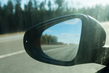 Fototapeta premium Rear view car mirror with defocused Road reflection. Selective focus. Suitable for any purpose use
