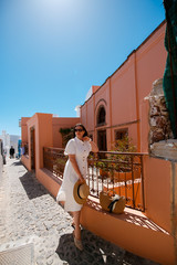 girl in a white dress in sunglasses looks away from a bright building