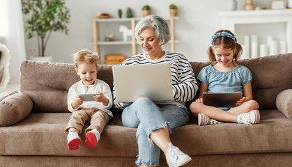 Senior woman with grandchildren using gadgets at home.