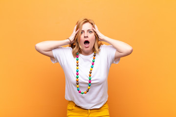 middle age woman feeling horrified and shocked, raising hands to head and panicking at a mistake