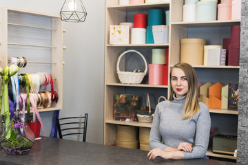 Woman florist stands at the reception in a flower shop. Small business representative