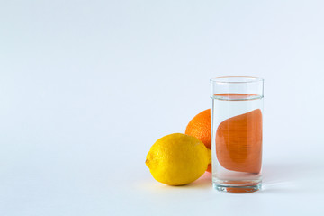 glass of water with ripe lemon and orange on white table. vitamin C to strengthen the immune system. Healthy lifestyle. citrus fruit on white background. copy space
