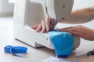 female hands sew a medical face mask during the period of flu, epidemic, pandemic of the...
