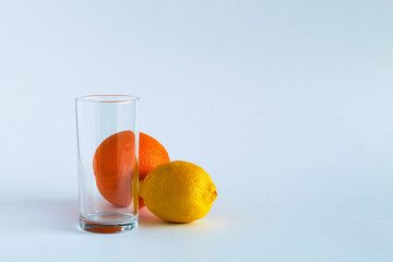 empty glass with ripe lemon and orange on white table. vitamin C to strengthen the immune system. Healthy lifestyle. citrus fruit on white background. copy space