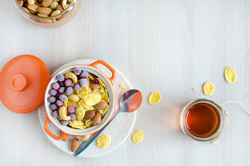 healthy lifestyle. nutritious breakfast on white wooden background, copy space. corn flakes with honey, berries, cranberries, nuts, cashews, almonds.