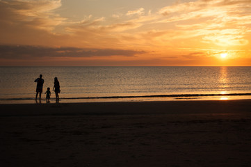 Family of three, mother, father and child, walking on the beach and looking at the sunset. Photo taken in Punta del Este, Uruguay.