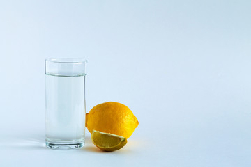 glass of water with ripe lemon and slice on white table. vitamin C to strengthen the immune system. Healthy lifestyle. citrus fruit on white background. copy space