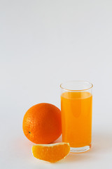 glass of fresh orange juice and oranges on the white background. whole citrus fruit with slice of orange on white table. vitamin C to strengthen the immune system. Healthy lifestyle. copy space.