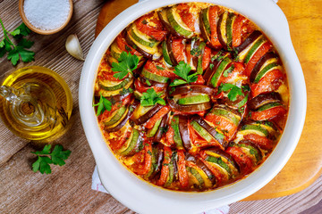 Cooked vegetable ratatouille with mozzarella cheese in white oven pan.