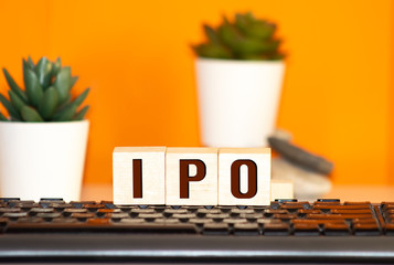 IPO Initial Public Offering written on a wooden cube in front of a laptop