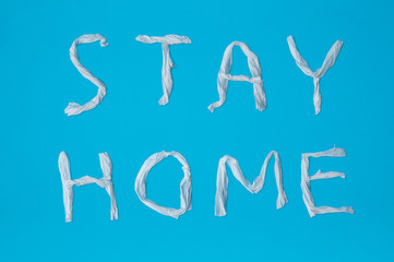 Words stay home made of toilet paper on blue background with shadow. Epidemic, social isolation, coronavirus COVID-19 concept